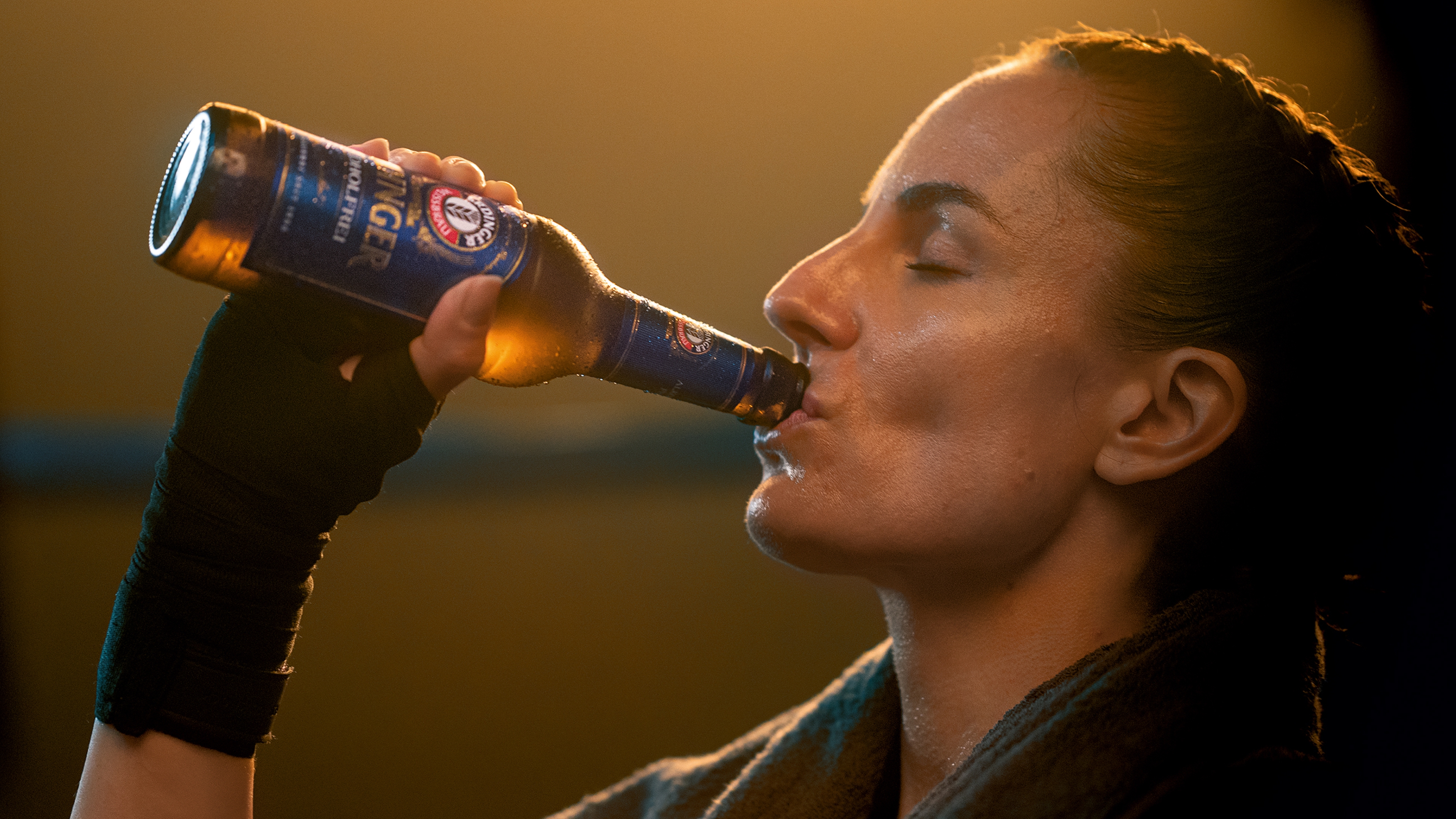 Eine Boxerin trinkt genussvoll ein ERDINGER Alkoholfrei nach dem Training.