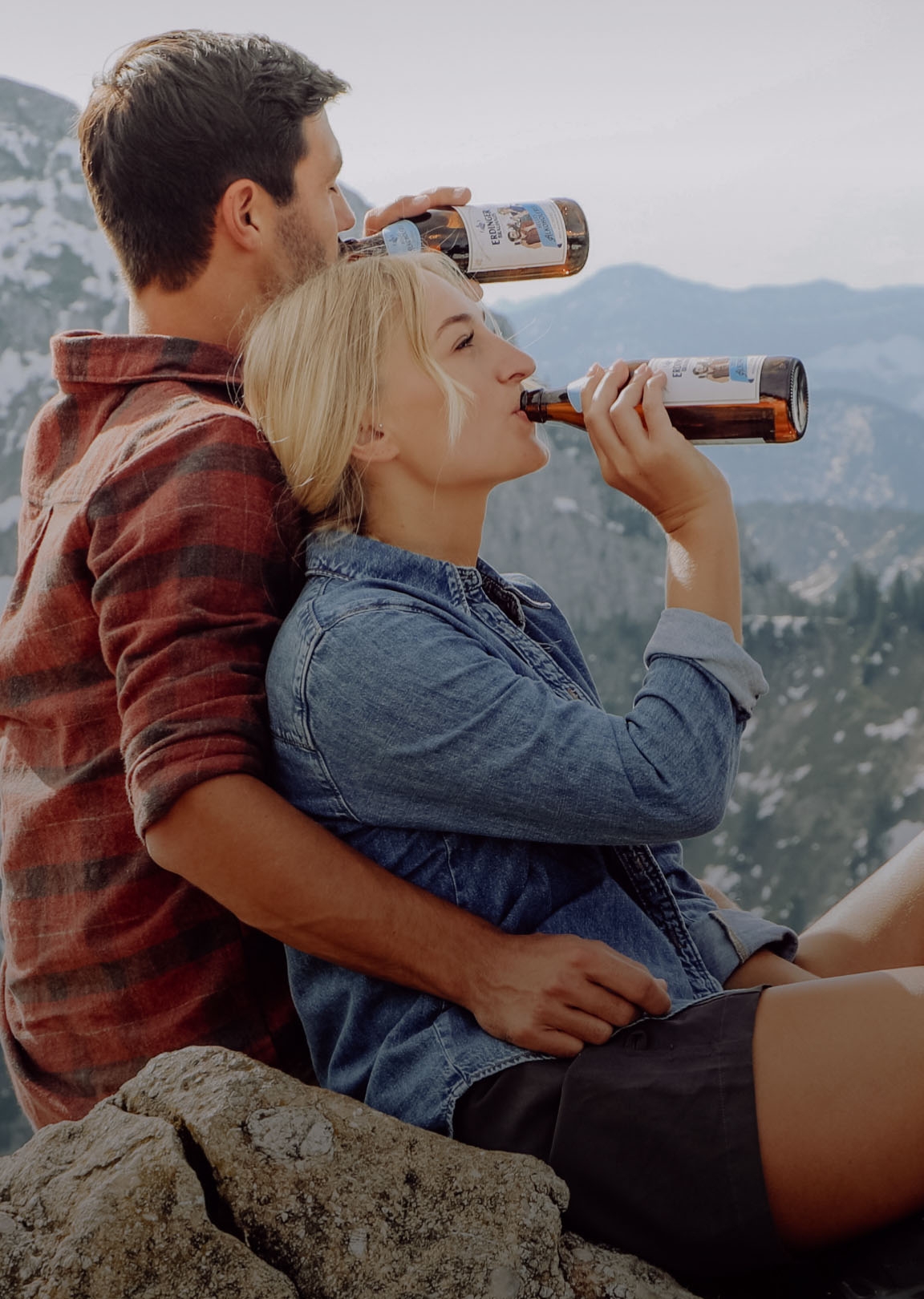 A woman is laughing and holding an ERDINGER Brauhaus Helles in her hand at a folk festival.