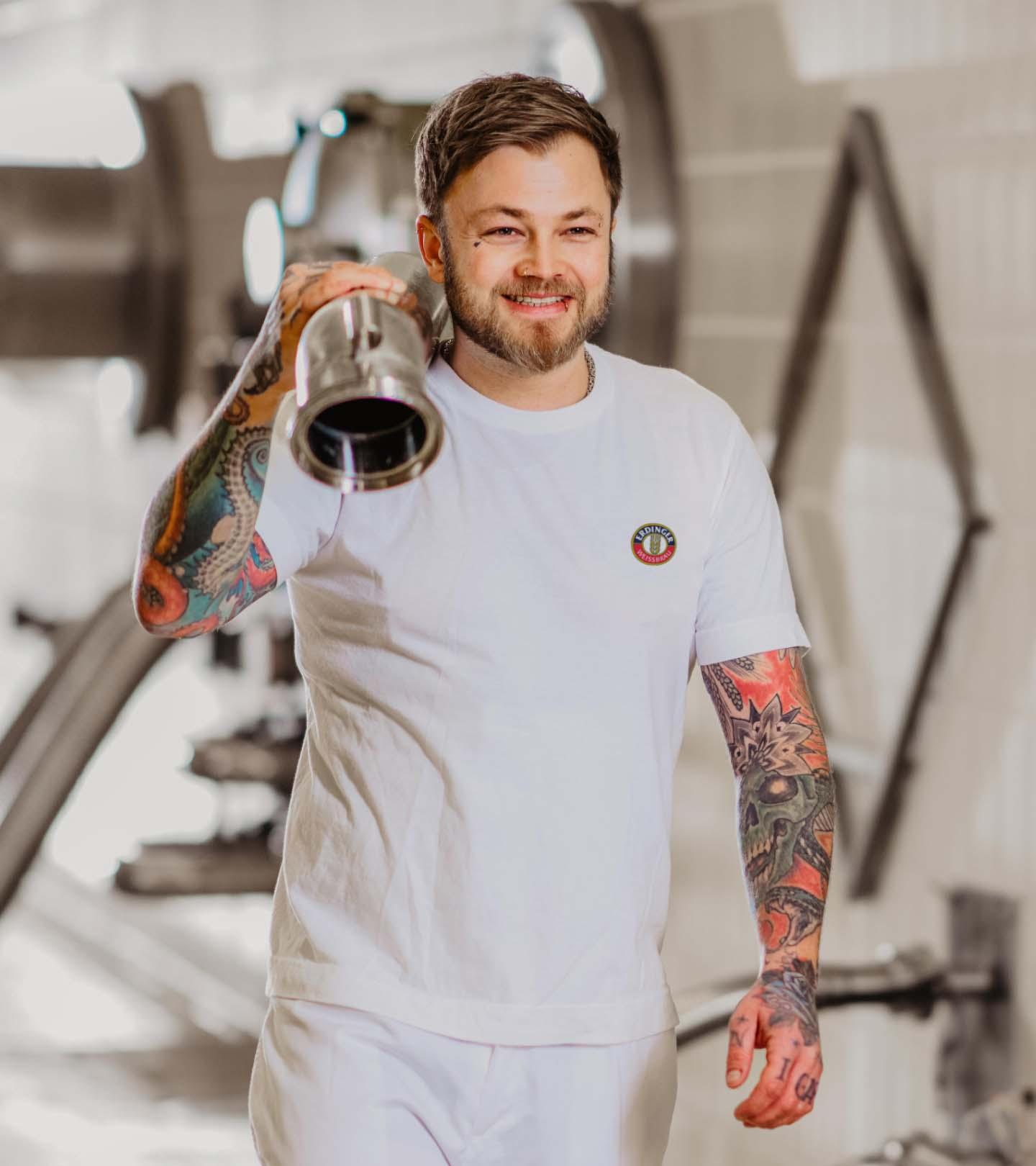 An ERDINGER brewer is carrying a hose.