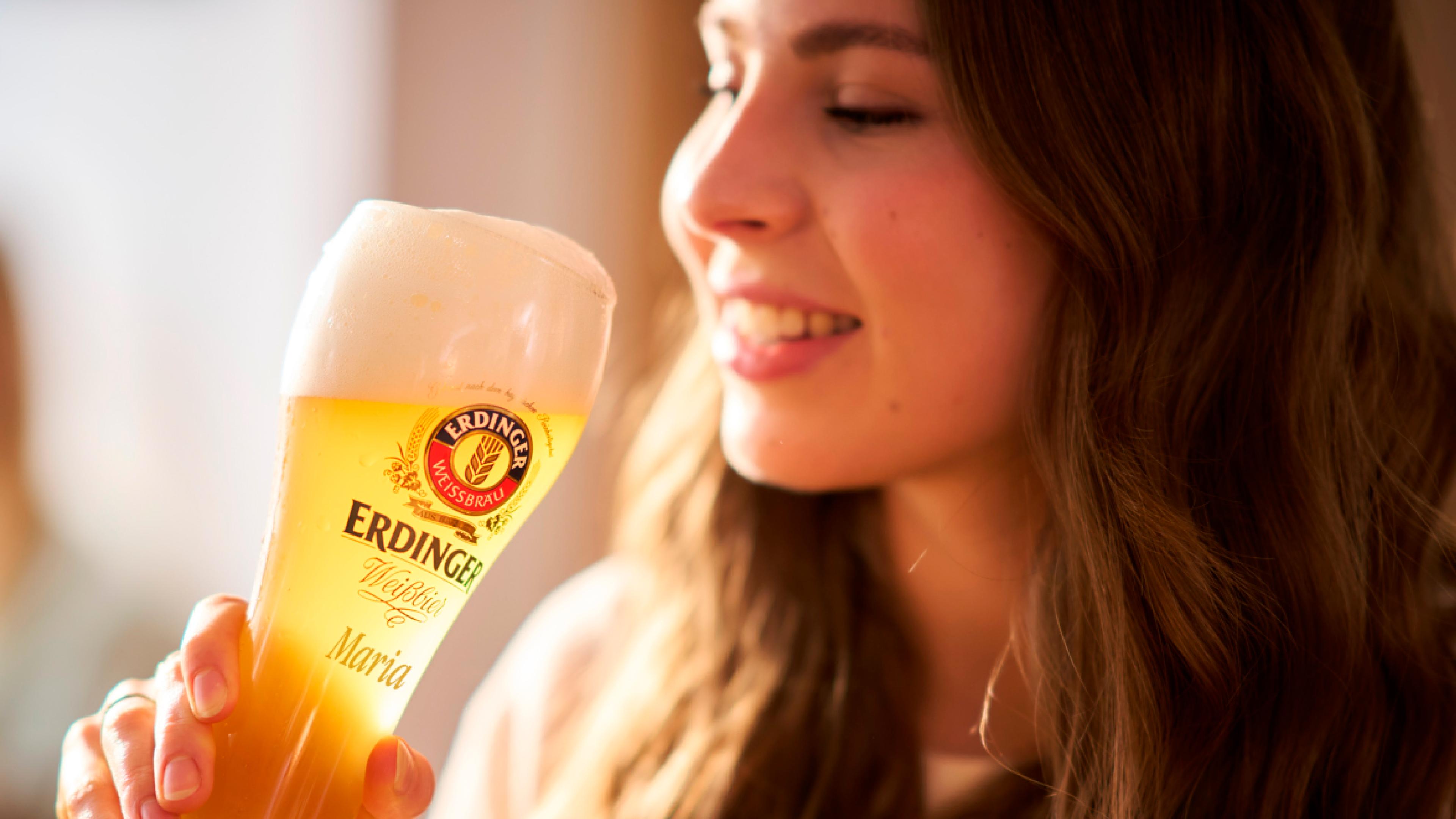 Several friends are raising a toast with Weißbier during the ERDINGER brewery tour.