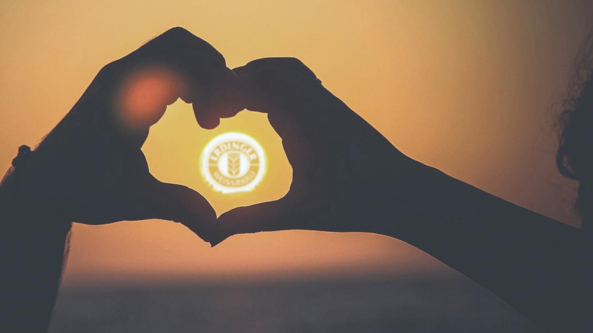 Hands form a heart around the setting sun with the ERDINGER logo, representing Fischer‘s donation check as a sustainability project.
