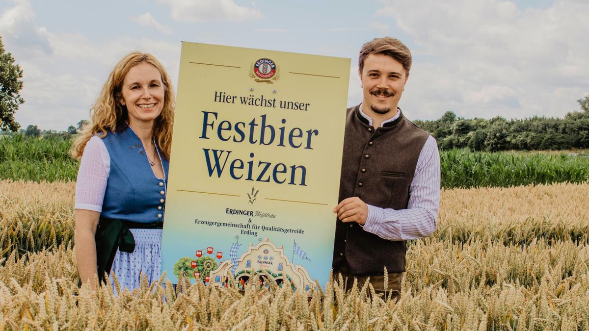 Alexandra Graf of ERDINGER and Daniel Gschlößl of the EZG pose together with the Festbier wheat sign in front of regional wheat.