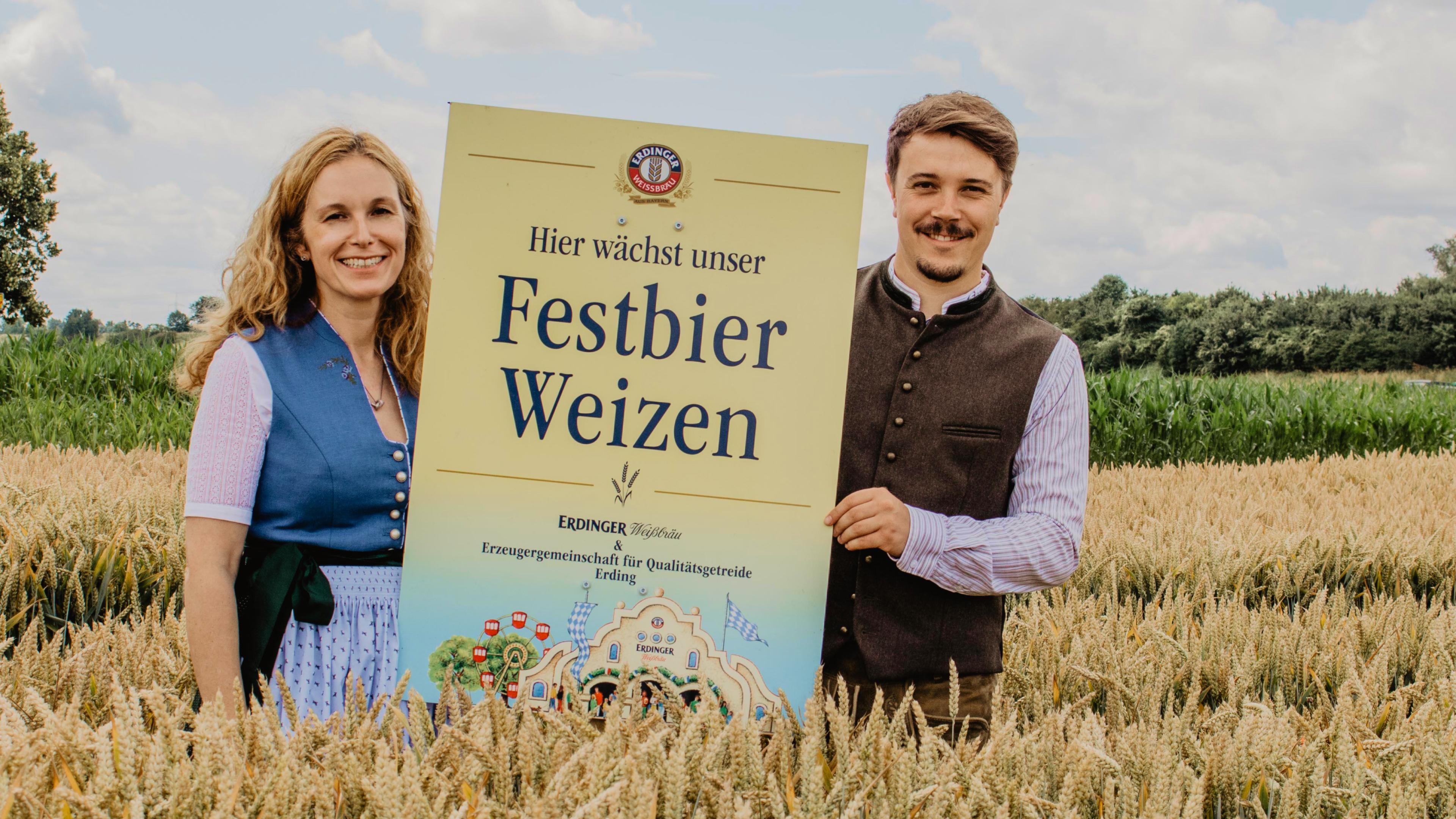 Alexandra Graf of ERDINGER and Daniel Gschlößl of the EZG pose together with the Festbier wheat sign in front of regional wheat.
