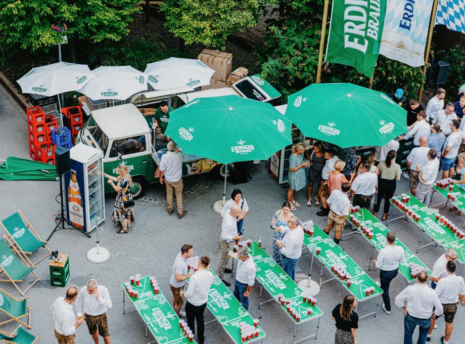 ERDINGER beer pong tables and umbrellas at a company event seen from a bird`s-eye view.