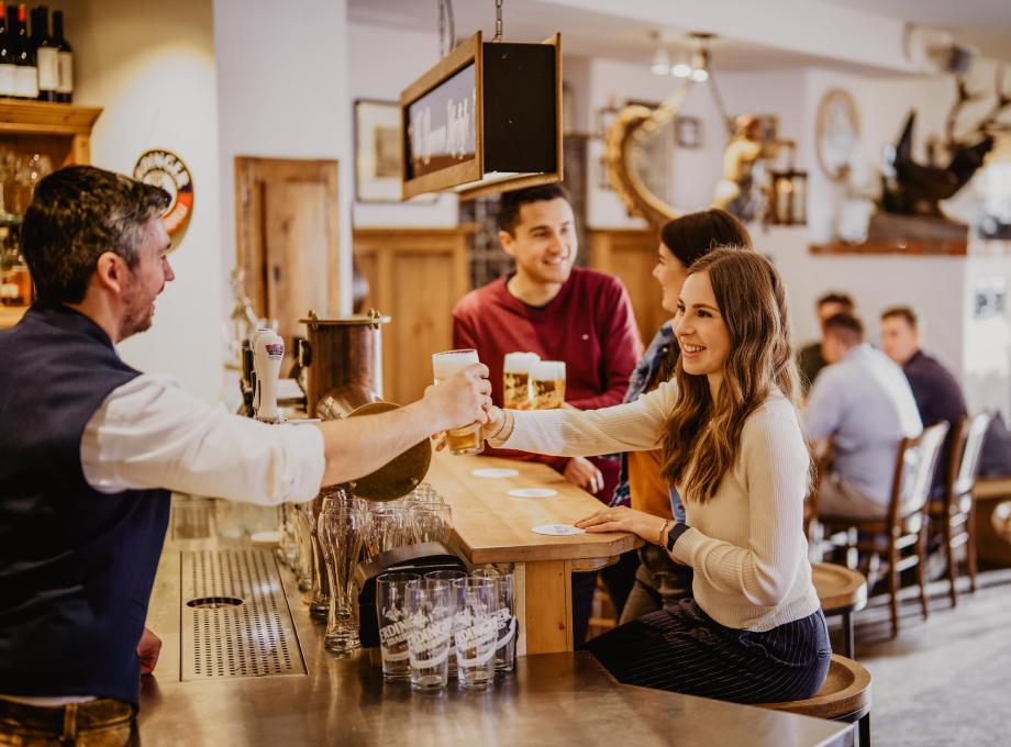 An ERDINGER employee is giving a colleague a beer at the bar counter.