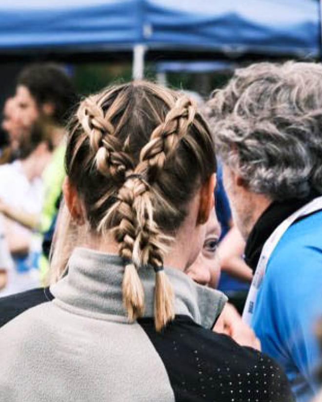 A woman with crossed braided pigtails from behind.