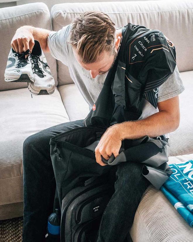 A man is sitting on a couch, checking his gear.