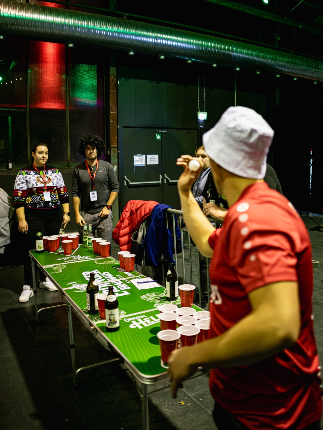 Two people are playing beer pong against each other on an ERDINGER Brauhaus beer pong table.