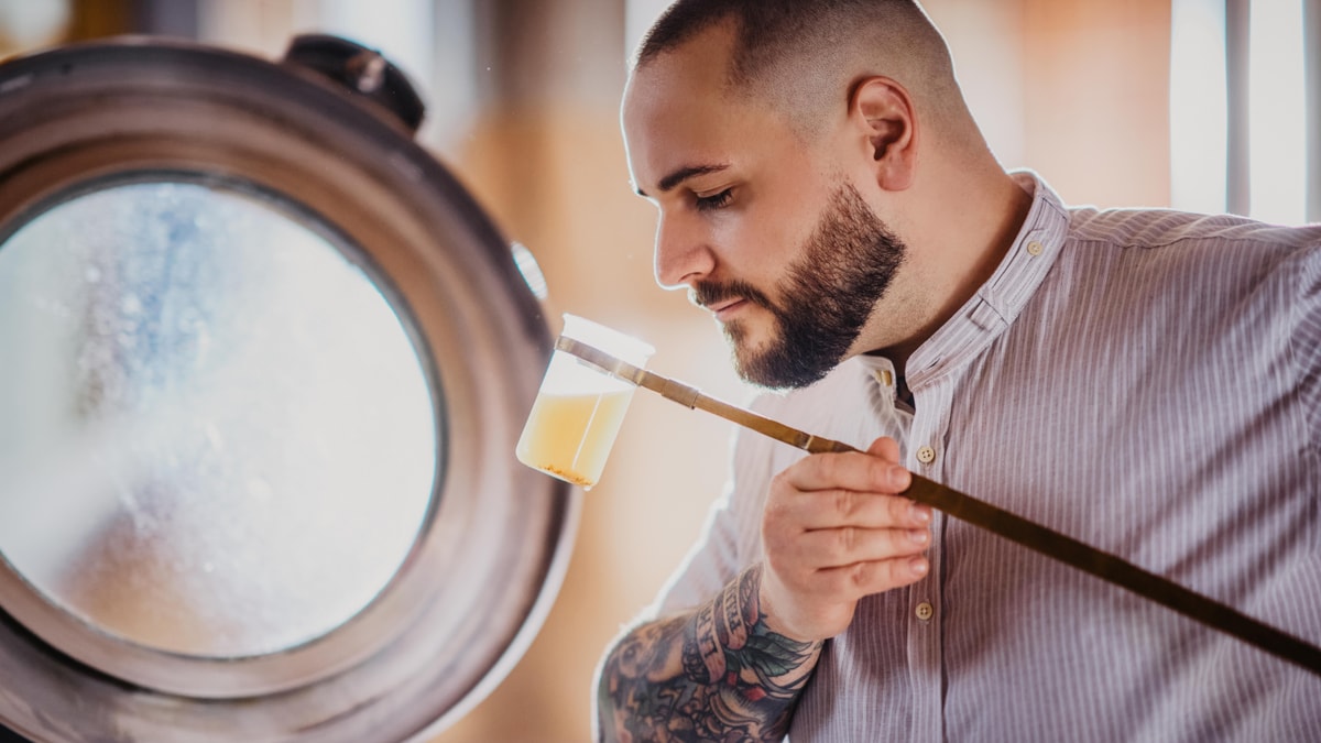An ERDINGER brewer smells a beer sample in a glass at the brewery.