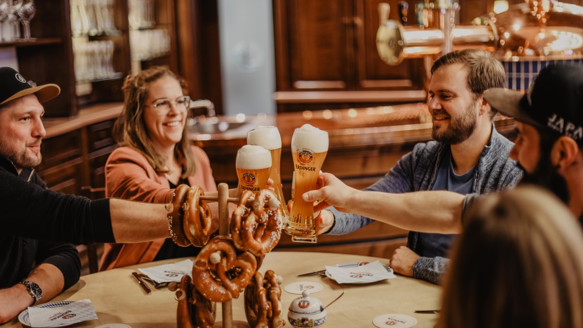 A group of friends are toasting with Weißbier during the ERDINGER brewery tour.