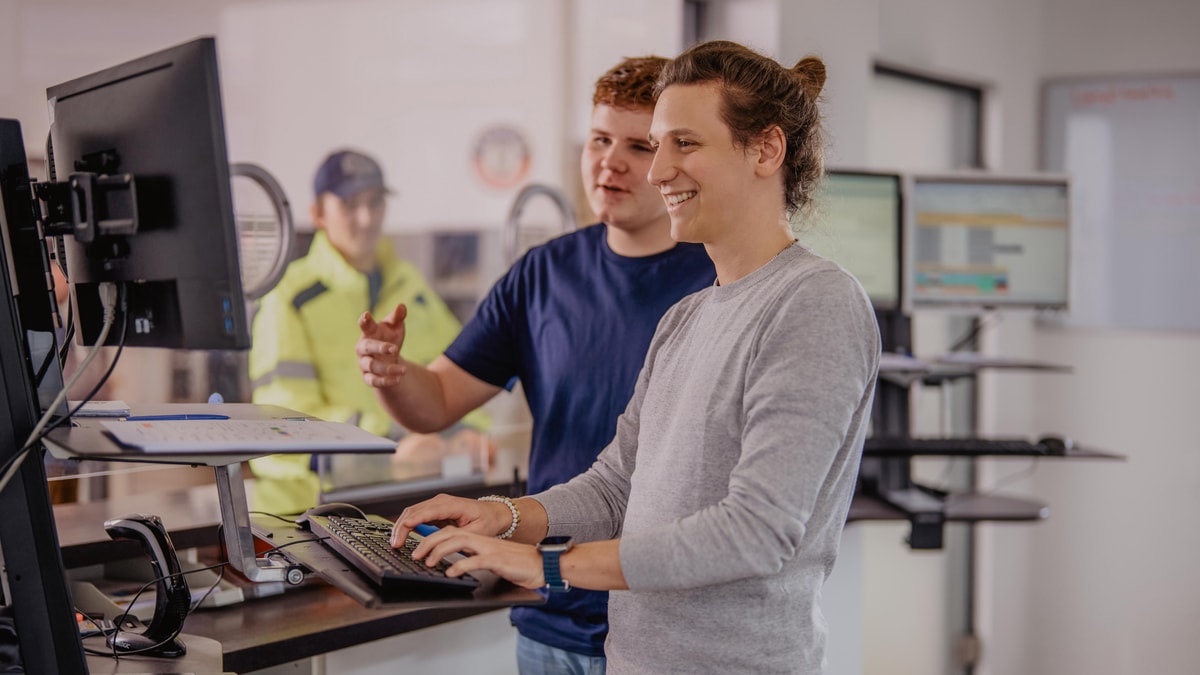 Two ERDINGER employees work together in front of a computer monitor in the brewery.