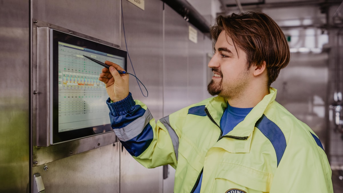 An ERDINGER employee operates a touchscreen on the wall in the brewery.