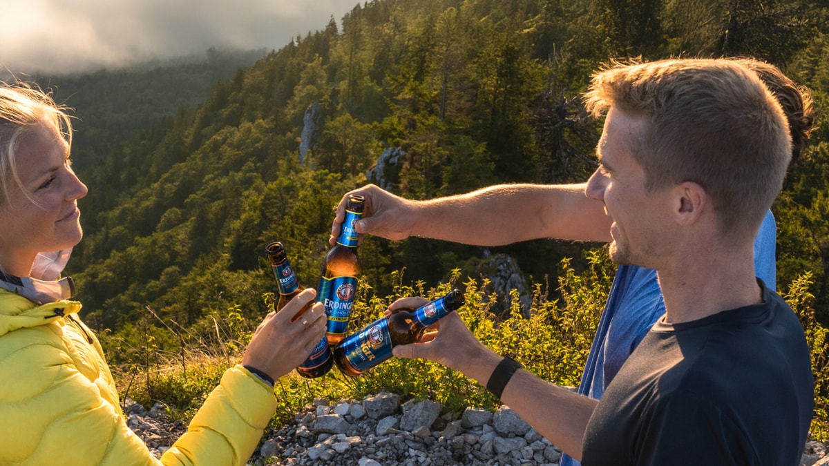 A man leans against a rock, enjoying a refreshing ERDINGER Alkoholfrei.