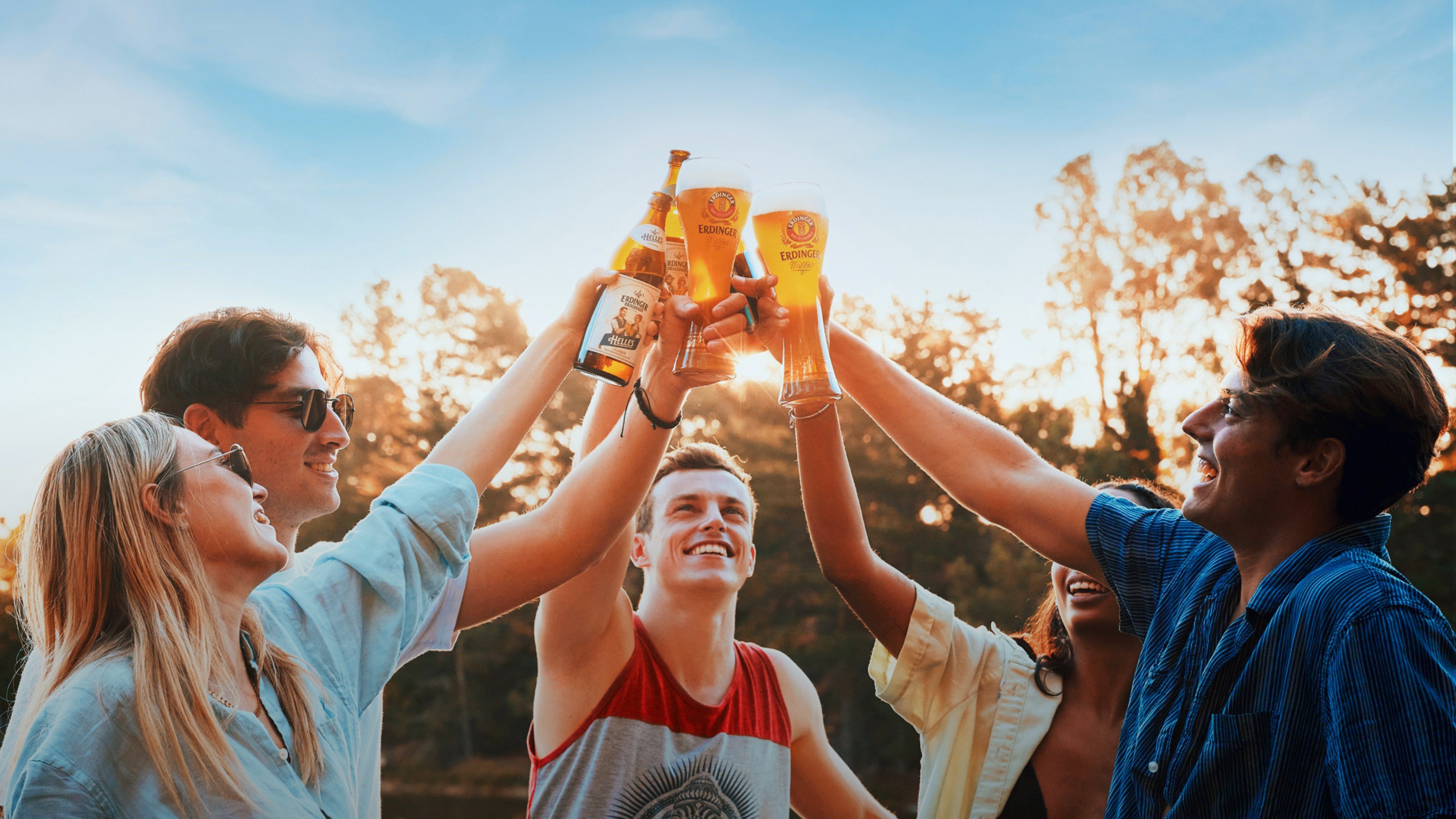 A few friends are toasting with different ERDINGER beer specialties on a sunny day.