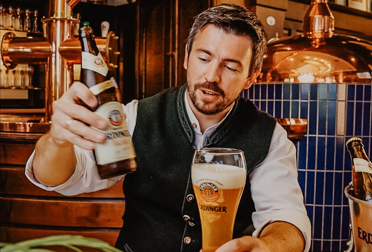 A bartender pours the yeast from the bottle onto the foam crown of the ERDINGER wheat beer.