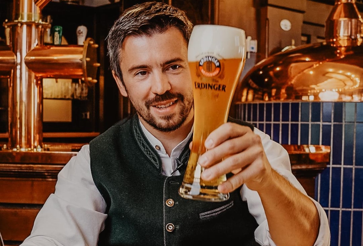 A bartender smiles and gives a thumbs-up with both hands.