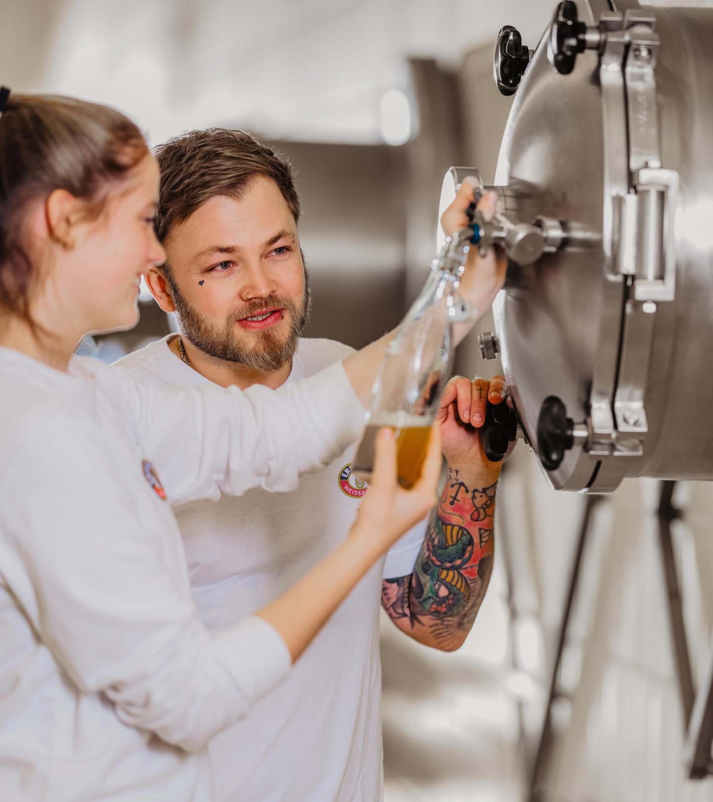 ERDINGER Brauer füllt zusammen mit einer Auszubildenden eine Bierprobe ab.