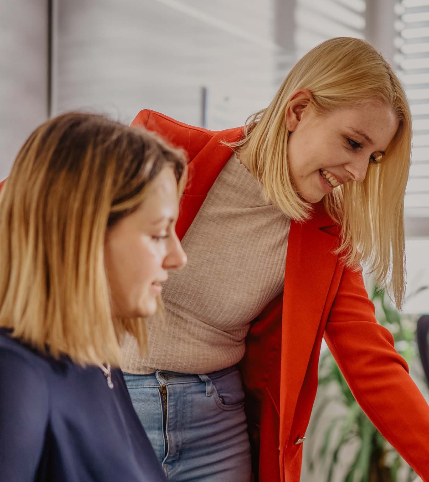 Eine ERDINGER Industriekauffrau zeigt einer Auszubildenden etwas.