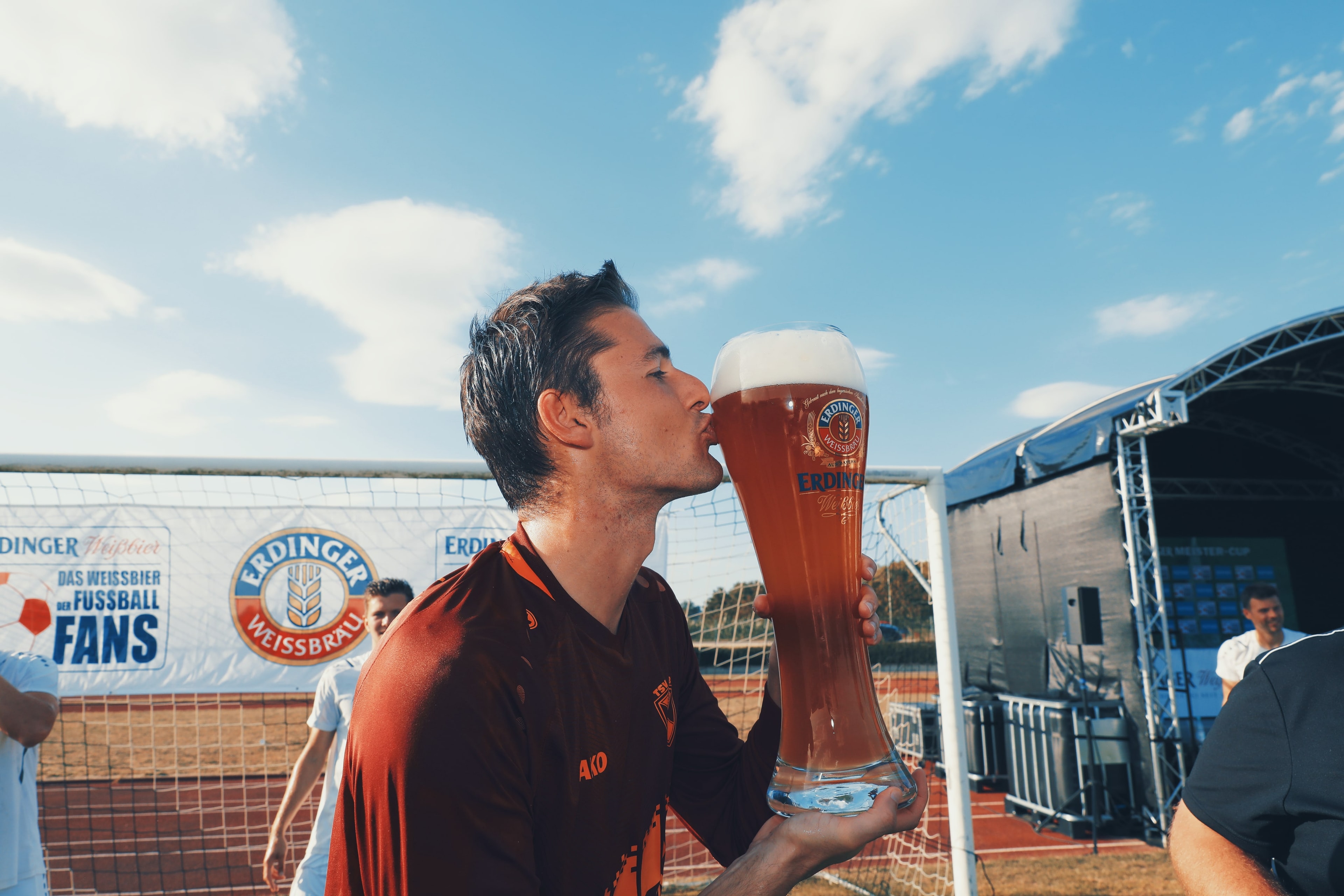 Ein Mann im Fußballtrikot küsst ein gefülltes ERDINGER 3-Liter Glas beim Meistercup.