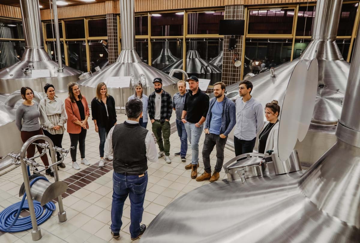 A group is standing in the ERDINGER brewhouse during a brewery tour.