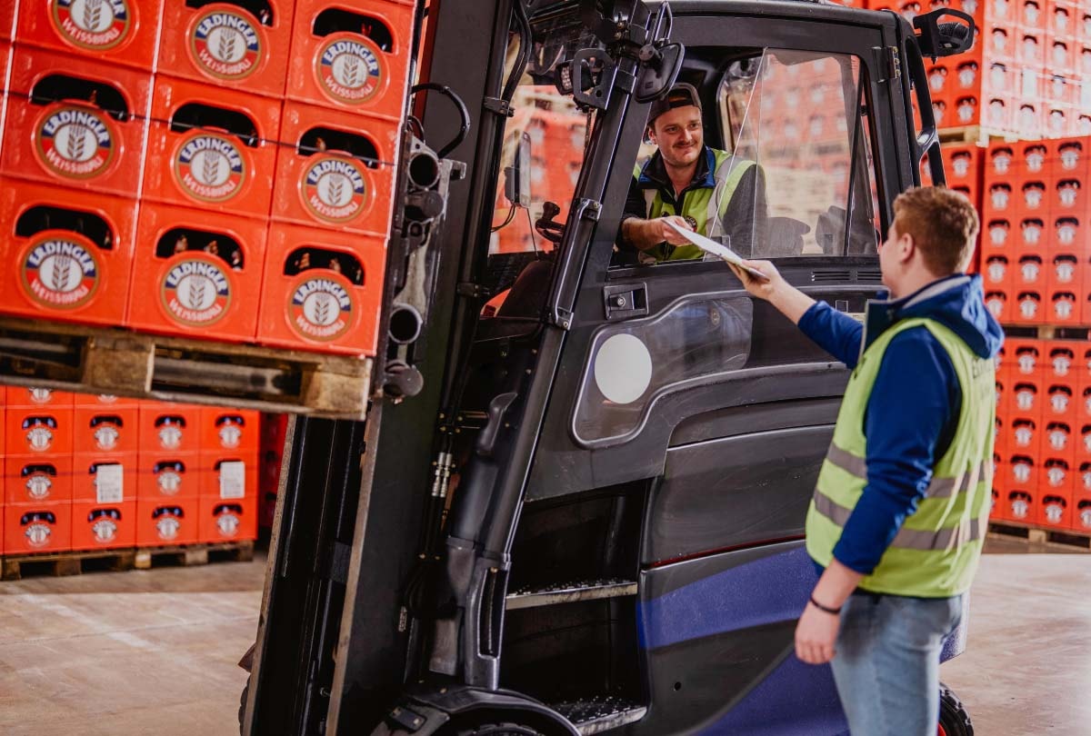 A forklift driver and an employee are having a conversation in the ERDINGER loading hall.