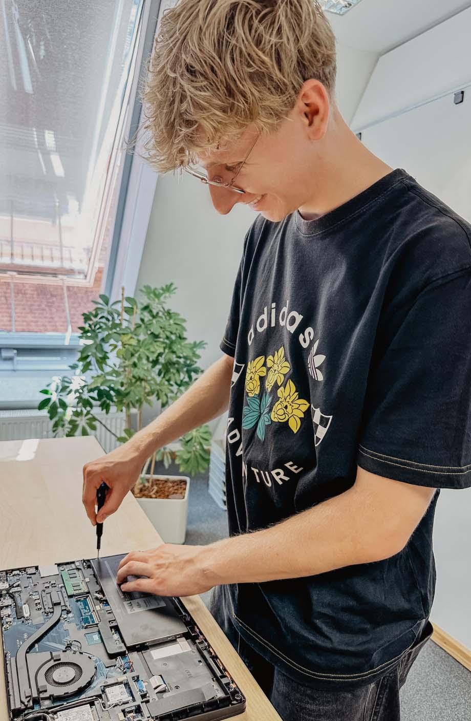 ERDINGER Fachinformatiker schraubt an offenem Laptop.