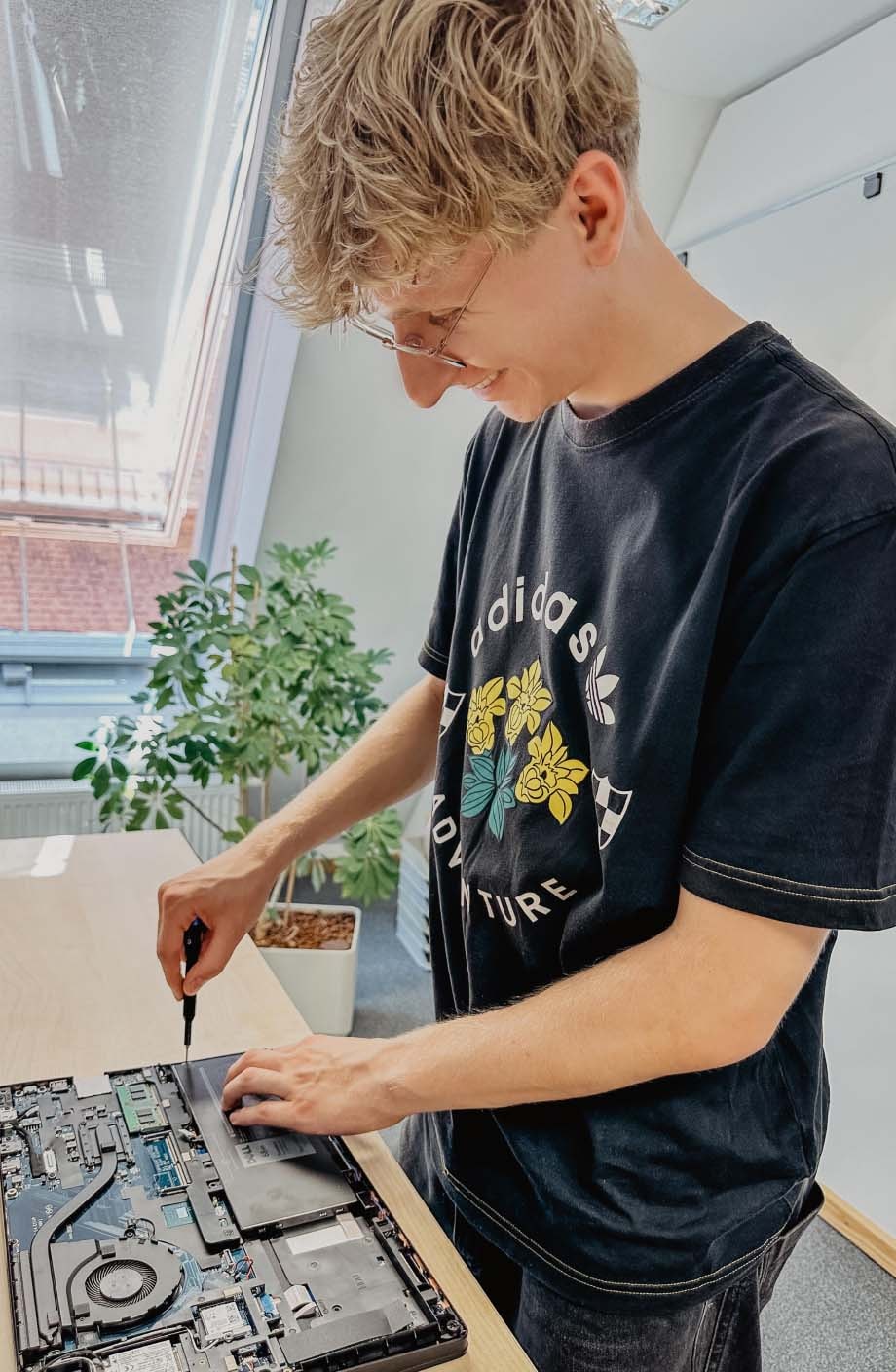 ERDINGER Fachinformatiker schraubt an offenem Laptop.