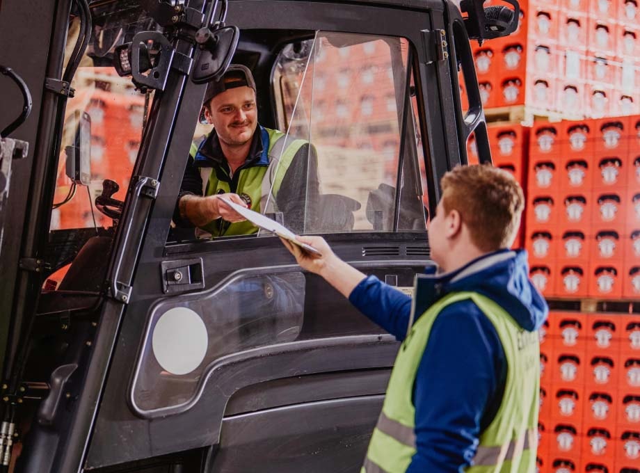 ERDINGER Lagerlogistik Auszubildender übergibt eine Liste an Staplerfahrer.