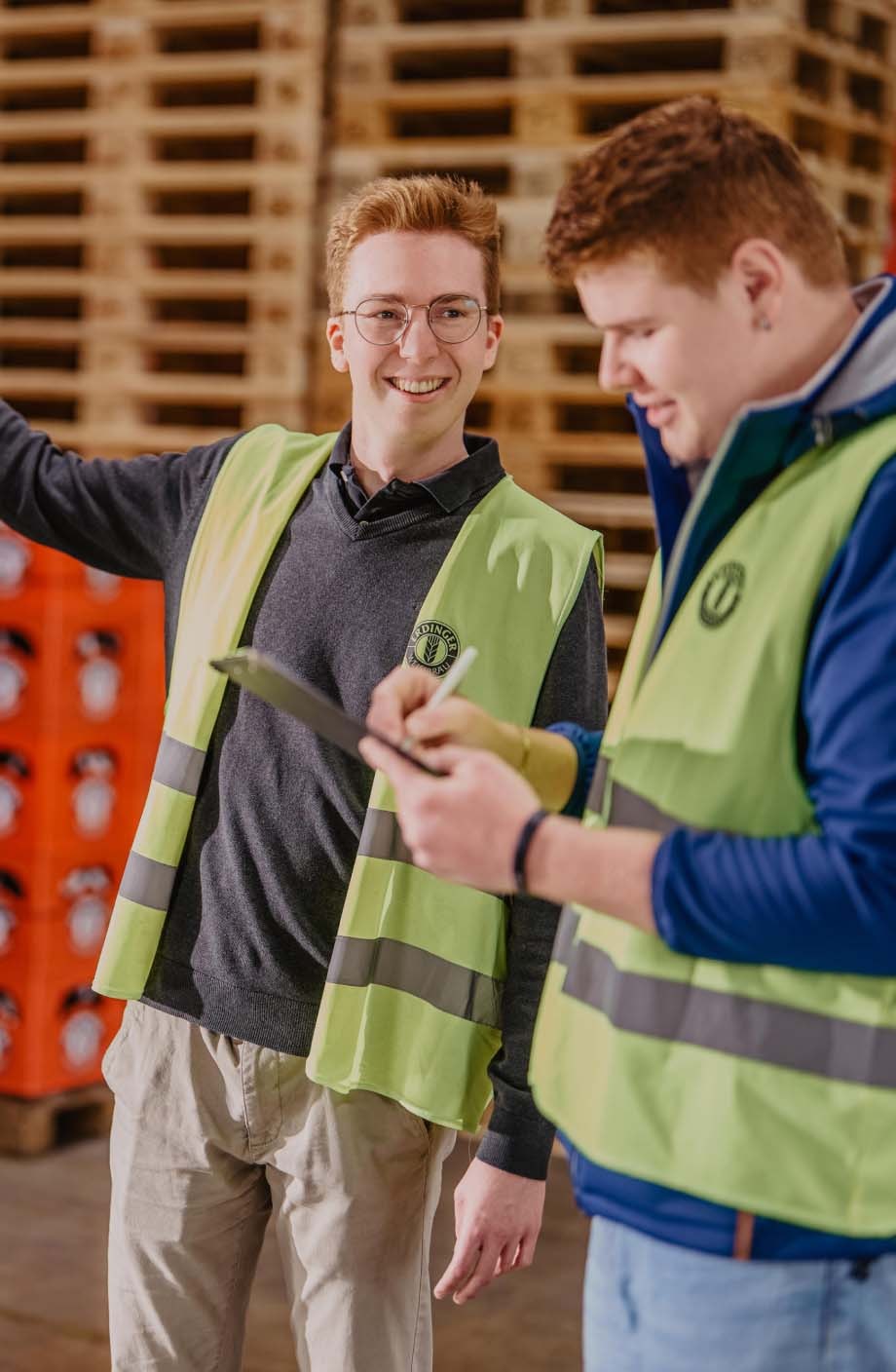 Zwei ERDINGER Lagerlogistiker gehen zusammen im Bierlager eine Inventarliste durch.