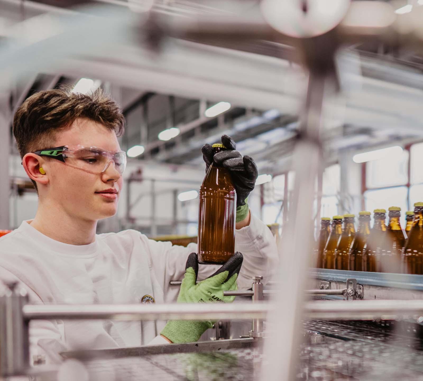 ERDINGER Lebensmitteltechniker prüft Qualität bei einer Flasche in der Füllerei.