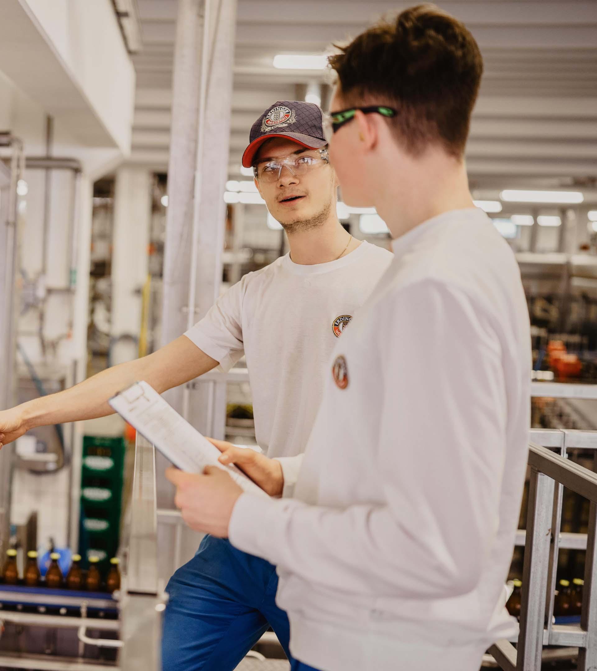 Zwei ERDINGER Lebensmitteltechniker arbeiten zusammen in der Füllerei.