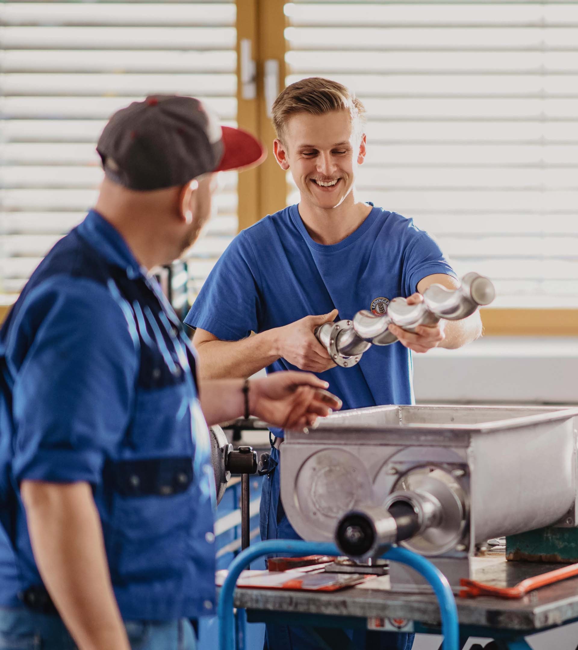 ERDINGER Industriemechaniker zeigt Kollegen ein Ersatzteil.