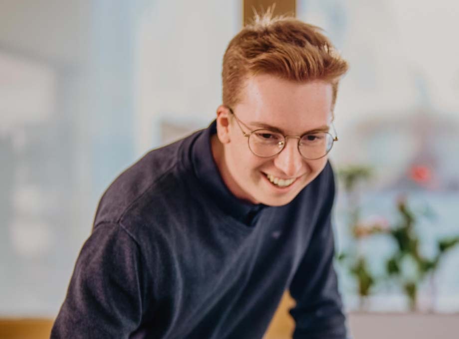 Ein ERDINGER Auszubildender Speditionskaufmann lächelt während der Arbeit.