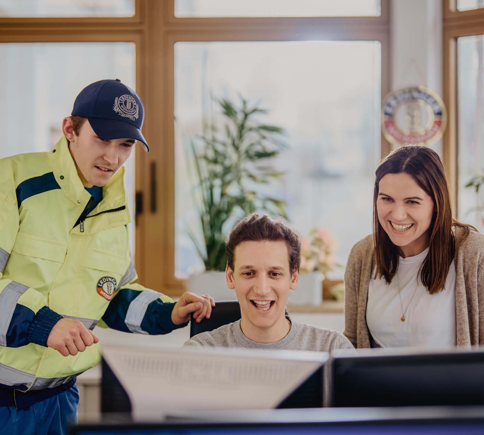 Ein Team aus drei ERDINGER Spedietionskaufleuten arbeitet zusammen in einem Büro.