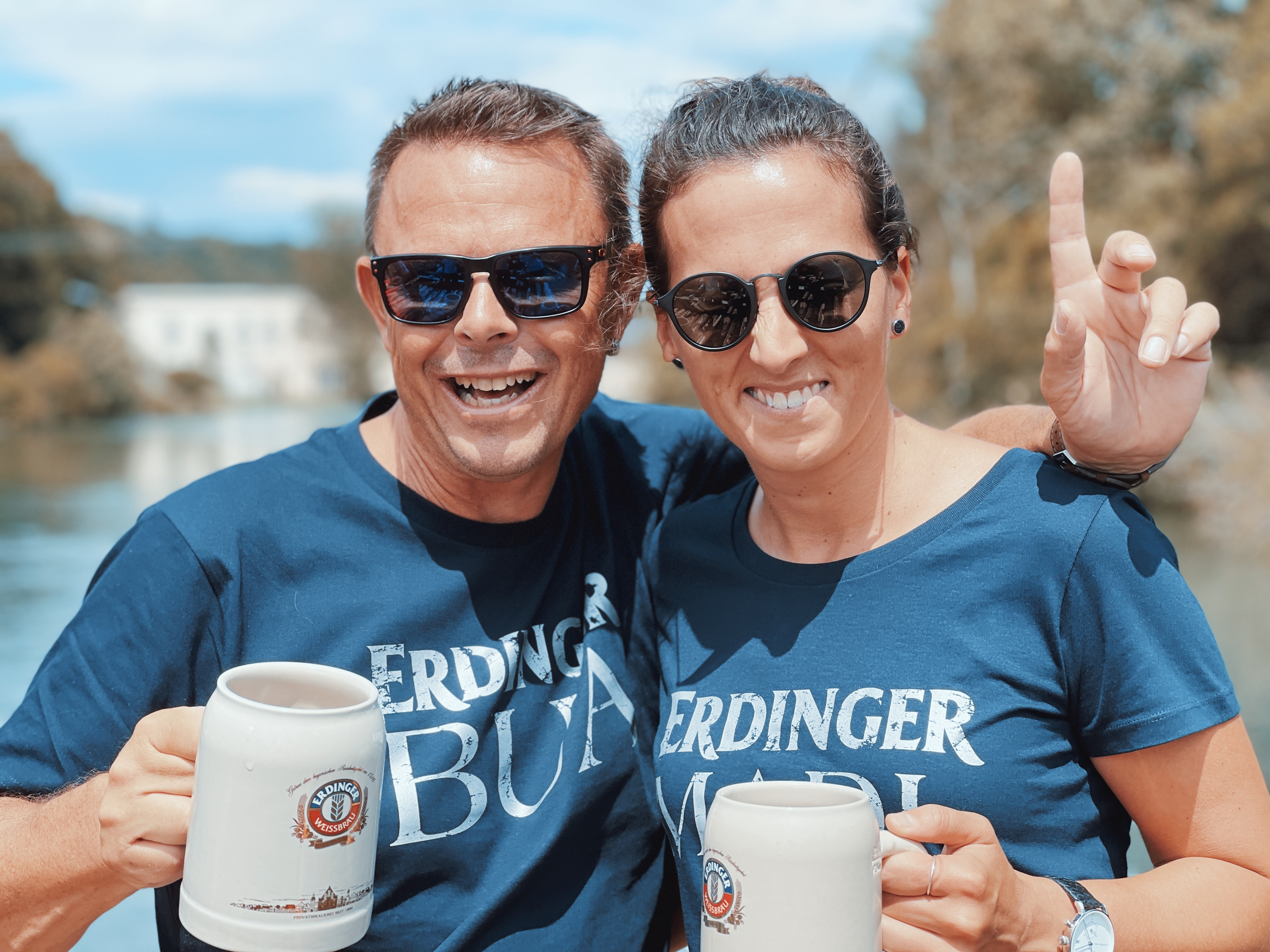 Zwei ERDINGER Fanclub Mitglieder mit ERDINGER T-Shirts und Steinkrügen lächeln.