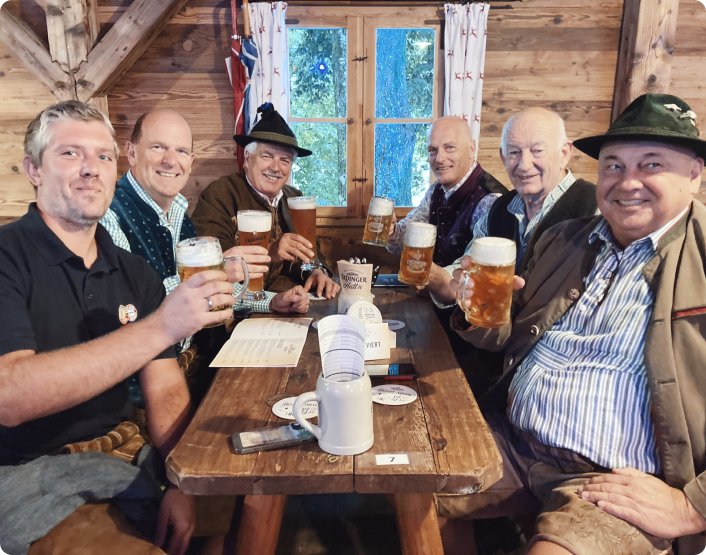 Männer in Tracht sitzen an einem Stammtisch und trinken ERDINGER.